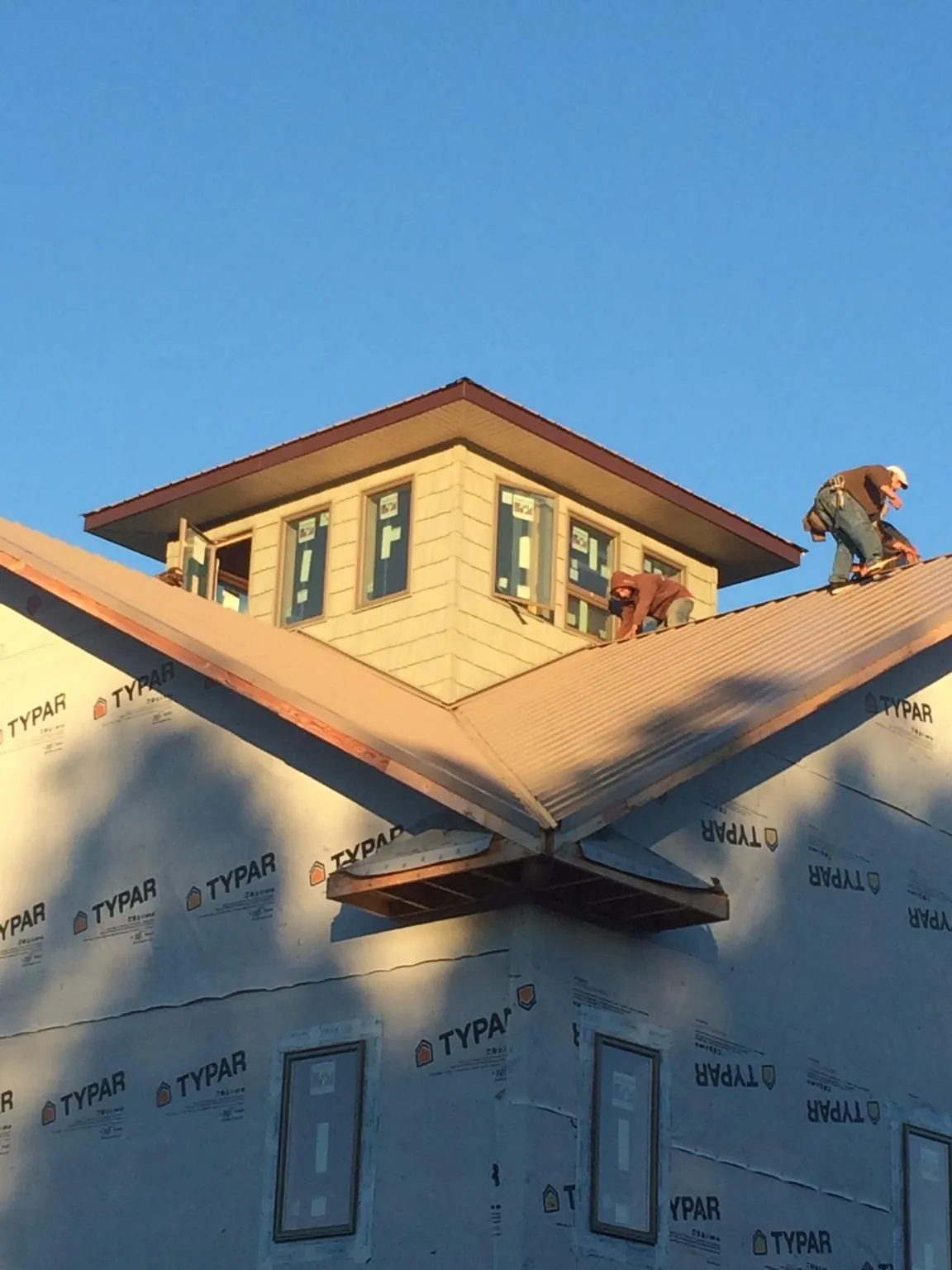 Roofers working around a rooftop cupola on a new metal roof at sunset — Roof Waterproofing in Wheaton by Roofing Brothers